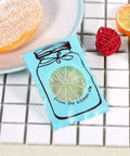Set of 100 Cute Plastic Candy Bags With Clear Window and Bottle Pattern, blue bag on tiled surface with fruit decor