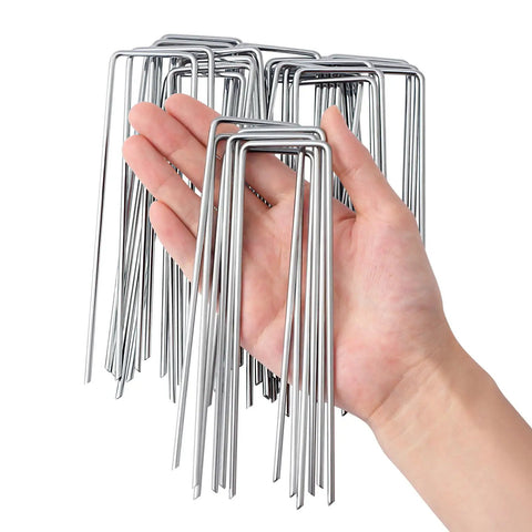 Hand holding Heavy Duty 6 Inch U-Shaped Landscape Staples Set, 120 Pack, 11 Gauge Galvanized Steel Garden Stakes