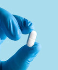 Straight Up Reliable Blue Nitrile Exam Gloves Latex Free And Powder Free For Clinics And Everyday Tasks Medium Size With Slick Surface And Tight Seal Case Of 1000 holding a white pill.