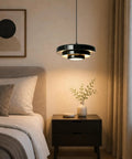 Black Swag Pendant Light Plug in, Mid Century Modern Pendant Lamp with Layered Metal Shade above a bedside table in a cozy bedroom.