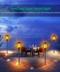 Lit Solar Flame Torch Lights For Outdoors With 99 LED Flickering Flames 43 Inch Waterproof Pathway Lights in a garden setting