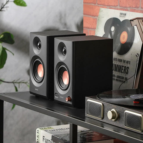 MR3 Powered Studio Monitors With Hi-Res Audio Certification And Bluetooth 5.4 on a desk beside records and player