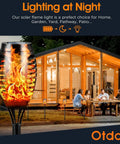Solar Torch Lights Outdoor Flickering Flame, 12 LED Waterproof Torches installed in a garden near a patio, safe faux flame lighting.