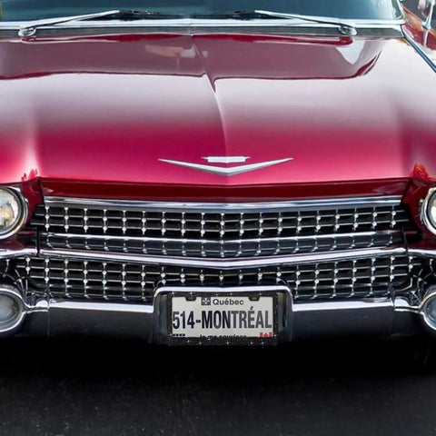 Front view of a vintage red car with a Sparkly Black License Plate Frame With Over 1200 14 Facets Crystal Rhinestones Bedazzled Glass Diamonds Scratch Guard Edges Includes Free Glitter Diamond Box Women Car Accessory.