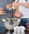 V Shaped 5 Qt Stainless Steel Mixing Bowl With Polished Finish next to two people cracking eggs