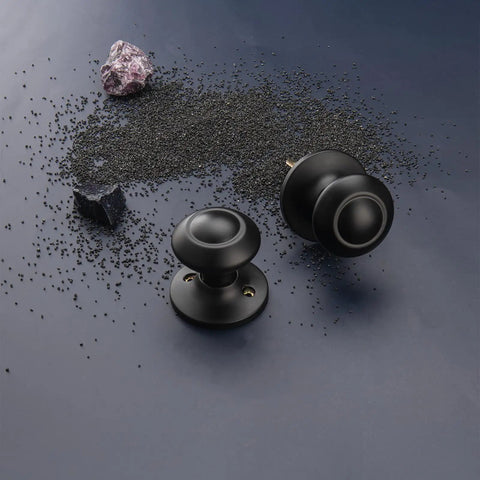 Black Interior Door Knobs Set Non Locking Privacy Hall Door Handle Vintage Vibe Lever With Smooth Edge And Easy Grip For Bedroom And Bathroom Doors Built To Last; Product displayed on scattered black particles with a dark background.