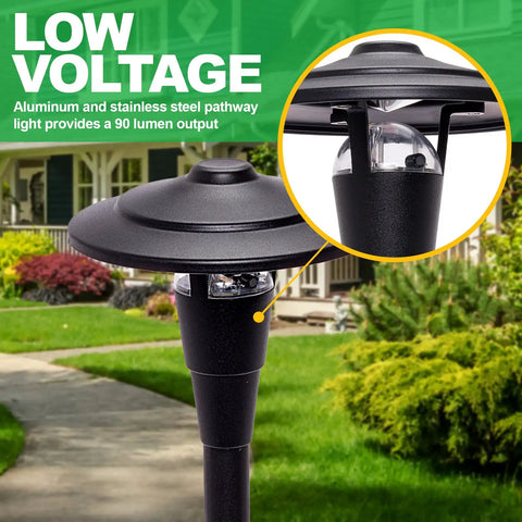 Close-up of low voltage outdoor path light in black metal finish, with a warm glow in garden setting, highlighting landscape.