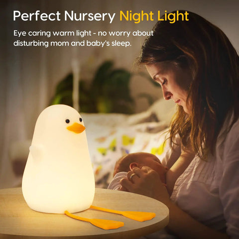Squishy Duck Night Light For Kids With Soft Warm Glow Silicone Dimmable Nursery Lamp on table near mother and baby.