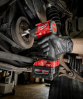 Hard Hitting Brushless Impact Wrench With Friction Ring Unleashes Knockout 1400 Foot Pounds Of Torque For Swift Socket Swaps And Beefy Fastening Tasks Compact 18 Volt Cordless Power Tool Built Like A Tank For Real World Applications in action under a vehicle.
