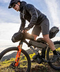 Cyclist using FrontLoader Bike Front Bag 8L For Light Camping Gear And Spare Clothes Green Durable Water-Resistant Build on trail.