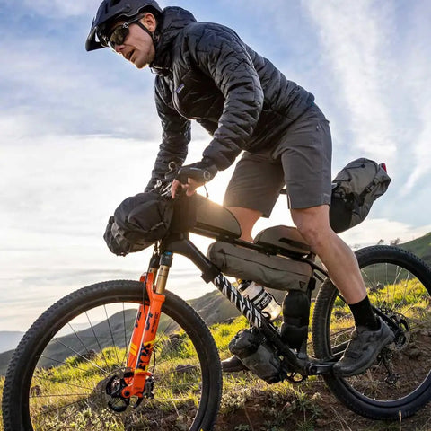 Cyclist using FrontLoader Bike Front Bag 8L For Light Camping Gear And Spare Clothes Green Durable Water-Resistant Build on trail.