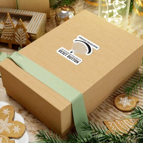 Gift box with Paragliding Sticker For Paramotor Pilots And Sky Enthusiasts Vinyl Decal on top, surrounded by holiday decor.