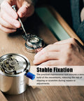 Person using Stainless Steel Watch Movement Holder With Fixed Jaw Non Adjustable Base For Automatic Watch Repair And Modding Pro Grade Tool Compatible With SKX007 7S26 7S36 NH35 NH36 4R36 on wooden table.