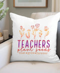 White decorative pillow on couch with floral design and quote "Teachers plant seeds that grow forever" in colorful text.