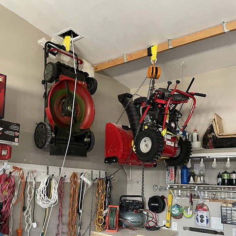 Lifting straps hanging from a ceiling beam in a garage, yellow nylon webbing used with a hoist.