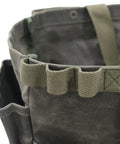 Close-up of waxed canvas firewood carrier tote for camping and garden work, collapsible and sturdy, with pockets in army green.