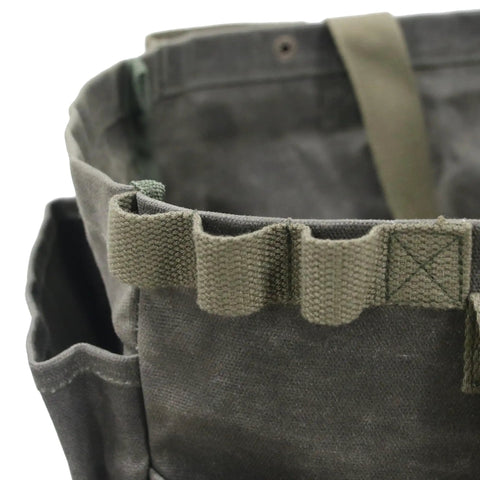 Close-up of waxed canvas firewood carrier tote for camping and garden work, collapsible and sturdy, with pockets in army green.