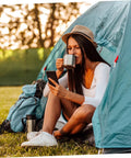Person sitting in a tent with a mug, enjoying the outdoors with 8 Piece Portable Stainless Steel Camping Cookware Set With Fire Resistant Pots And Bowls