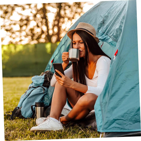 Person sitting in a tent with a mug, enjoying the outdoors with 8 Piece Portable Stainless Steel Camping Cookware Set With Fire Resistant Pots And Bowls
