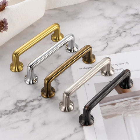 Four metal cabinet pulls on marble surface, including Antique Brass Cabinet Pulls 10 Pack With 3-3/4 Inch Hole Centers, Vintage Brass Handles