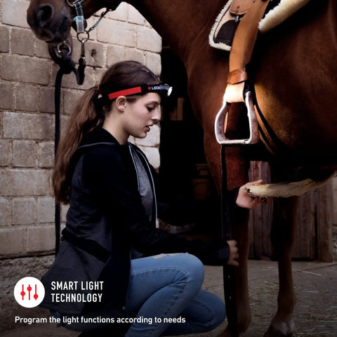 Person adjusting horse saddle wearing Ultimate Hands Free Headlamp Blasting Six Hundred Lumens Up To One Hundred Fifty Meters Away Great For Work Hard Hats And Nighttime Adventures With Red Rear Safety Light And Advanced Focus System Lightweight At One Hundred Fifty Eight Grams