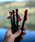 Hand holding stakes for Waterproof Hammock Rain Fly Tarp With Stakes And Carry Bag For Backpacking Ultralight Camping Shelter Ripstop Nylon