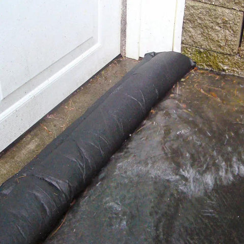 Grab And Go Flood Kit With Ten Five Foot Flood Barriers Water Activated Expands Up To Three And A Half Inches High When Wet Provides Up To Fifty Feet Of Flood Protection Per Bucket No Sand Or Labor Needed Store In Vehicle Or Closet Orange barrier blocking water at door.