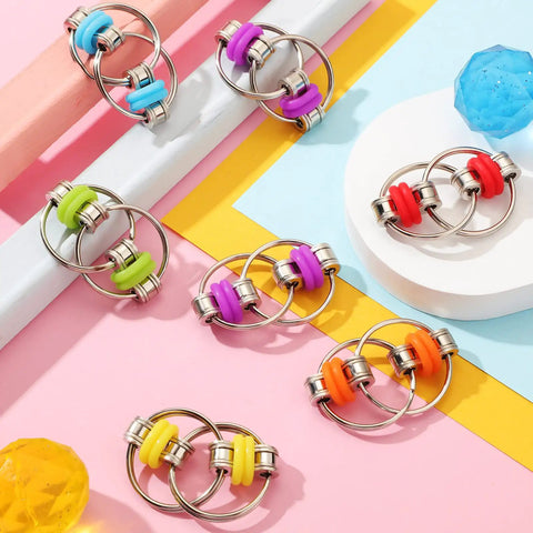 Dope Ten Pack Bike Chain Fidget Flippy Key Rings For Stress Relief And ADHD, colorful silicone, stainless steel, displayed on pastel surface.