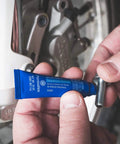 Blue Medium Strength Thread Locker For Bolts And Fasteners Quarter Inch To Three Quarter Inch Keeps Vibration From Loosening Seals Leaks And Corrosion Removable With Hand Tools 36 Milliliters being applied to a bolt.