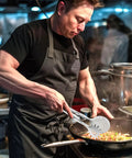 Chef using stainless steel frying tongs for cooking