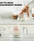 Three Piece Glass Measuring Cups Set With 1 Cup 2 Cup And 4 Cup Sizes, milk being poured into clear measuring cup with readable marks.
