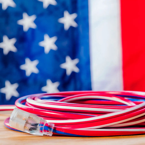 Patriotic 50 Foot 12 Gauge Heavy Duty Extension Cord With Lighted Plug For Indoor Outdoor Use All Purpose Contractor Grade SJTW Red White And Blue -40F To 140F Proud Partner Of Wounded Warrior Project coiled in front of a flag
