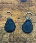 Two black RFID hotel key fobs from 50 Pcs Pack Re-Writable RFID Hotel Key Fobs For 13.56MHz Locks, Compatible With RC522 PN532 Readers.