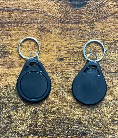 Two black RFID hotel key fobs from 50 Pcs Pack Re-Writable RFID Hotel Key Fobs For 13.56MHz Locks, Compatible With RC522 PN532 Readers.