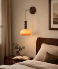 Flyrose Set of 2 Vintage Caramel Glass Wall Sconces Mid Century Modern Lamp hanging above a bedside table with a book.