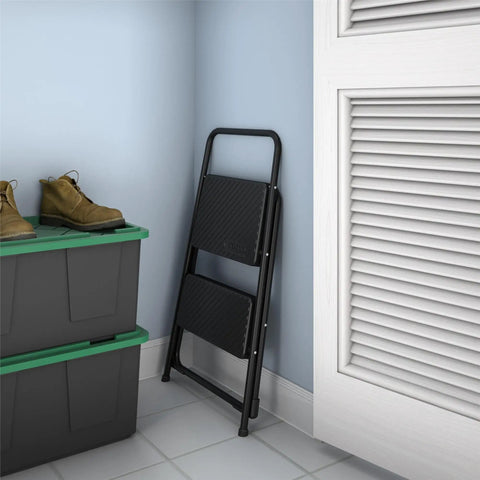 Lightweight Two Step Home Stool For Easy Reaching And Cleaning With Non Marring Feet in folded position, compact design next to storage boxes.