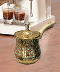 Decorative Turkish coffee pot with long handle beside espresso machine on kitchen counter