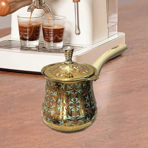 Decorative Turkish coffee pot with long handle beside espresso machine on kitchen counter