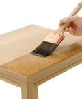 Applying Fast Drying Oil Based Polyurethane Wood Finish In Warm Satin Tone on a wooden table surface with a brush.