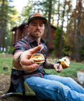 Man offering s'more while sitting on lightweight outdoor chair for stadium seats camping hiking and more water resistant adjustable straps