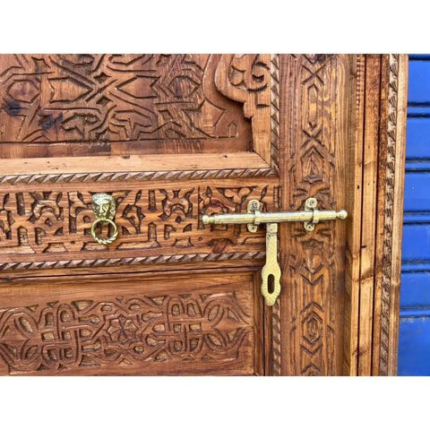 Close-up of hand carved solid wood barn door with intricate patterns and brass locker, rustic antique style.