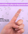 Close-up view of finger holding 360 Piece Galvanized Hog Ring Kit With Angled Pliers For Upholstery Includes Three Quarter Inch, One Half Inch, And Three Eighths Inch Rings Pro DIY Installation Kit For Bungee Cords And Cushions on lavender background, showing ring size and details.