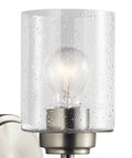 Close-up of Winslow 9.25 Inch Wall Sconce In Brushed Nickel With Clear Seeded Glass showcasing light bulb and textured glass.