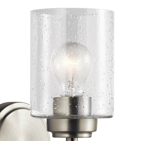 Close-up of Winslow 9.25 Inch Wall Sconce In Brushed Nickel With Clear Seeded Glass showcasing light bulb and textured glass.