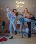 Three girls in a bedroom with My Happy Place Neon Sign Warm White Neon Lights For Bedroom Decor Cozy Home Office Wall Art Wedding And Birthday Party Decor Gift For Girls Room Modern Neon Wall Sign glowing above.