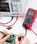 Person using Handy Digital Multimeter M2K0R With Auto Ranging DC And AC Voltmeter on a circuit board, testing continuity.