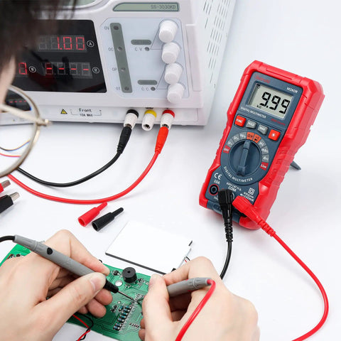 Person using Handy Digital Multimeter M2K0R With Auto Ranging DC And AC Voltmeter on a circuit board, testing continuity.