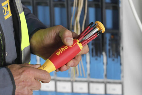Person holding Insulated SlimLine Ultra Driver Blade Set with Slotted and Phillips Bits, 7 Piece Kit, in front of panel wiring.