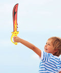 A child playing with a flame-designed foam sword from the Foam Sword And Shield Set For Kids 12 Piece Ninja Warrior Viking Role Play Gear.