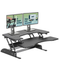 Pro Plus 36 Adjustable Desk Converter With 11 Height Settings for dual monitors, black, shown on table with screens